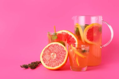 Renkli arka planda gözlük ve bir sürahi lezzetli greyfurt limonatası.