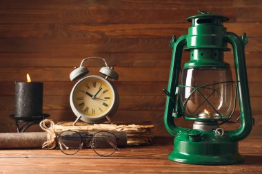 Eski moda lamba, çalar saat ve ahşap arka planda gözlük.