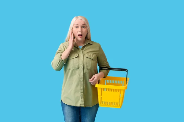 一个带着彩色背景购物篮的惊讶的成熟女人 — 图库照片