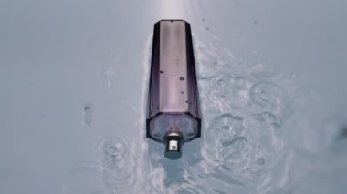 Hafif arka planda suda bir şişe parfüm.