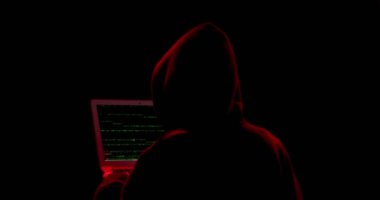 Karanlık arka planda dizüstü bilgisayarı olan bir hacker silueti