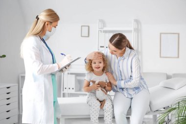 Küçük kızıyla birlikte bir kadın klinikteki çocuk doktorunu ziyaret ediyor.