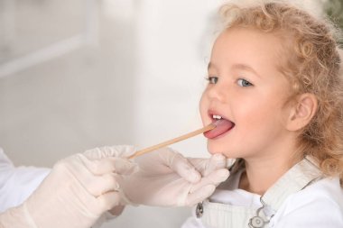 Pediyatrist küçük kızı klinikte muayene ediyor.