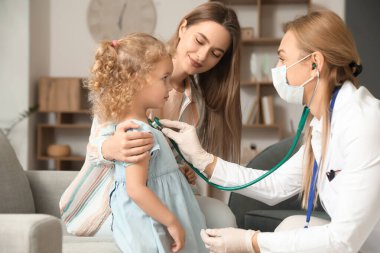 Pediyatrist küçük kızı evde muayene ediyor.