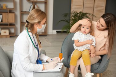 Pediyatrist küçük kızı evde muayene ediyor.