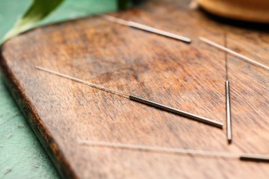 Ahşap tahtada akupunktur iğneleri, yakın plan.