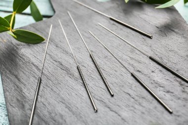 Ahşap tahtada akupunktur iğneleri, yakın plan.