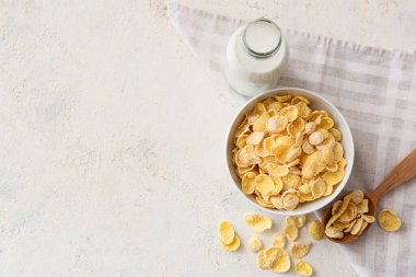 Lezzetli mısır gevrekleri ve arka planda bir şişe sütle dolu bir kase.