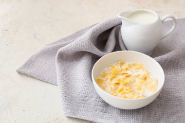 Lezzetli mısır gevrekleri ve hafif arka planda sütle dolu bir kase.