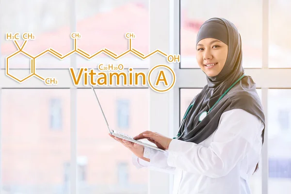 臨床でビタミンAのラップトップと化学構造式を持つイスラム教徒の医師 — ストック写真