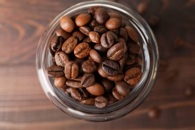 Kahve çekirdekli kavanoz ve ahşap arka plan.