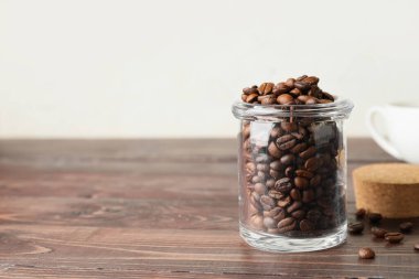 Kahve çekirdekli kavanoz ve ahşap arka plan.