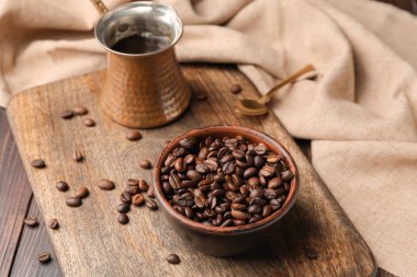 Kahve demliği ve kase, ahşap arka planda fasulye.