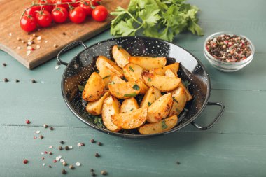 Ahşap arka planda maydanozlu patates kızartma tavası.