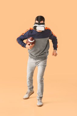 Sanal gerçeklik gözlüklü sportif genç adam arka planda Amerikan futbolu oynuyor.