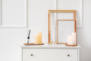 Işık duvarının yanındaki çekmecelerde mumlar ve boş çerçeveler yakıyor.