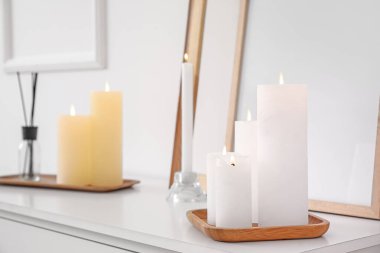 Işık duvarının yanındaki çekmecelerde mumlar ve boş çerçeveler yakıyor.