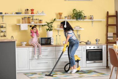 Anne ve kızı mutfakta halı süpürürken eğleniyorlar.