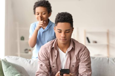 Küçük çocuk evde kardeşine eşek şakası yapıyor.