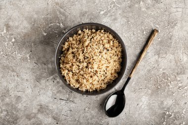 Lezzetli kinoalı kase ve gri arka planda kaşık.