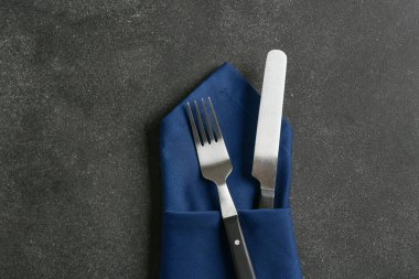 Koyu arkaplanda çatal bıçak takımı ve şık peçete.