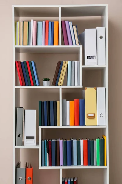 Shelf unit with books near light wall