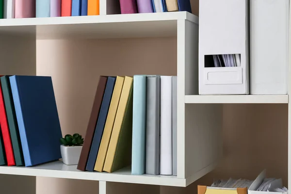 Shelf unit with books near light wall