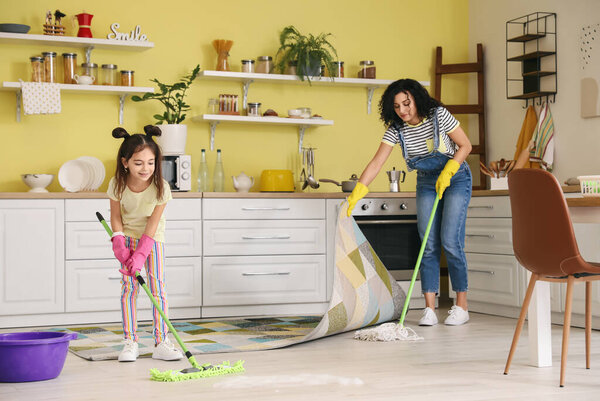 Mother and daughter mopping floor in kitchen
