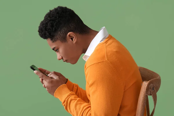 Teenage boy with bad posture using mobile phone on color background