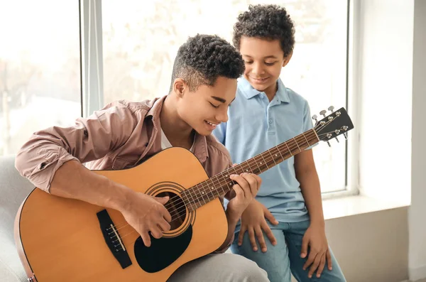 Adolescente Con Hermano Pequeño Tocando Guitarra Casa — Foto de Stock