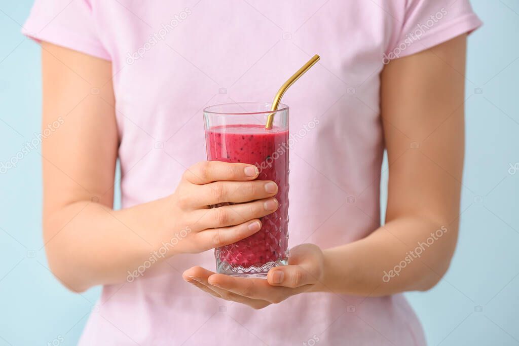 Woman with glass of fruit smoothie on color background