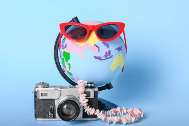 Arkaplanda fotoğraf makinesi ve güneş gözlüğü olan dünya