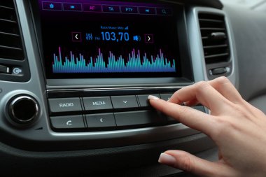 Arabadaki radyo istasyonunu dinleyen bir kadın.