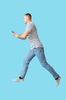 Renkli arka planda cep telefonu olan zıplayan genç adam