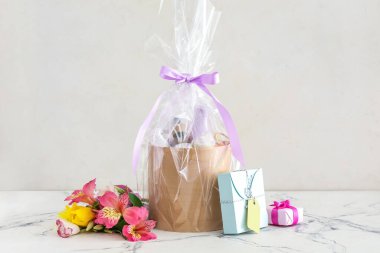 Kozmetik ürünleri ve arka planda çiçekler olan hediye sepeti.