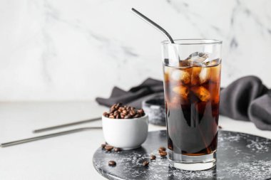 Bir bardak soğuk bira ve hafif arkaplanda kahve çekirdekleri.