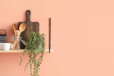 Mutfak eşyaları renkli duvarda asılı rafta.