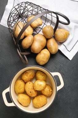 Esmer arka planda çiğ patatesli tencere ve sepet.