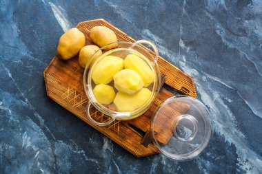 Arka planda soyulmuş patatesli tencere.