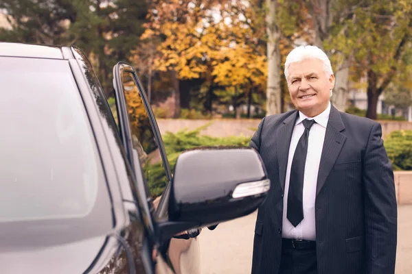 Senior businessman opening car door