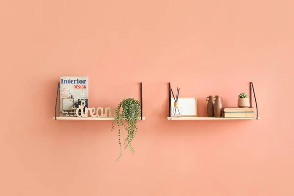 Shelves with magazine and decor hanging on color wall