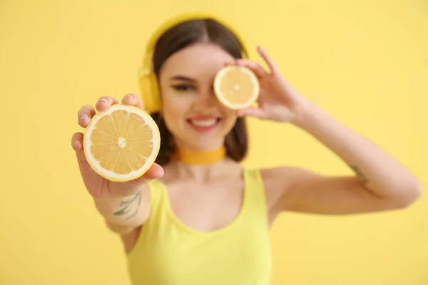 带着黄色背景的切柠檬的时髦年轻女子 — 图库照片