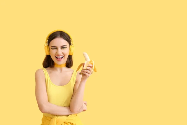 黄色の背景にヘッドフォンやバナナとスタイリッシュな若い女性 — ストック写真