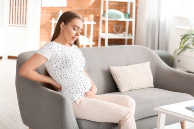 Evde sırt ağrısı çeken hamile bir kadın.