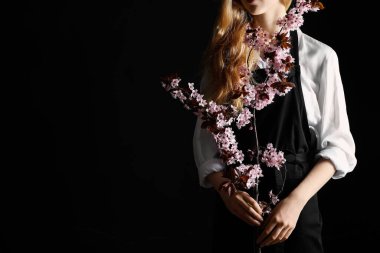 Koyu arkaplanda çiçek açan dalları olan güzel bir kadın.