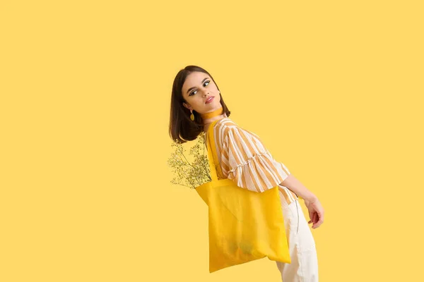 穿着黄色背景购物袋的时髦年轻女子 — 图库照片