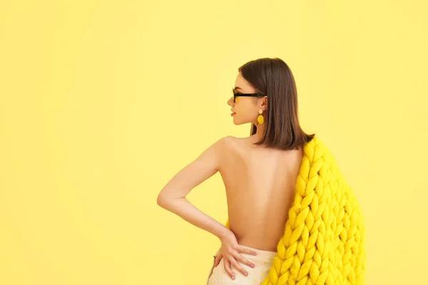 黄色の背景にニットプレイとサングラスを持つスタイリッシュな若い女性 — ストック写真