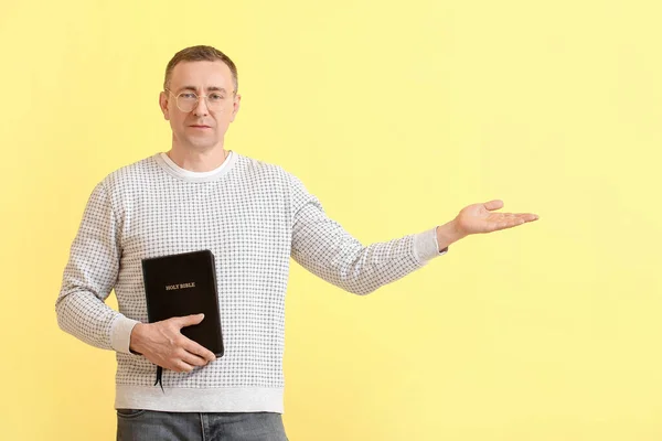 Człowiek Biblią Pokazuje Coś Kolorowym Tle — Zdjęcie stockowe