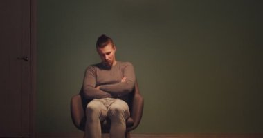Depresyondaki genç adam karanlık odada oturuyor.