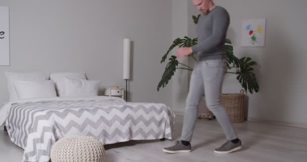 家で靴ひもを結ぼうとする慢性腰痛を持つ若い男 — ストック動画